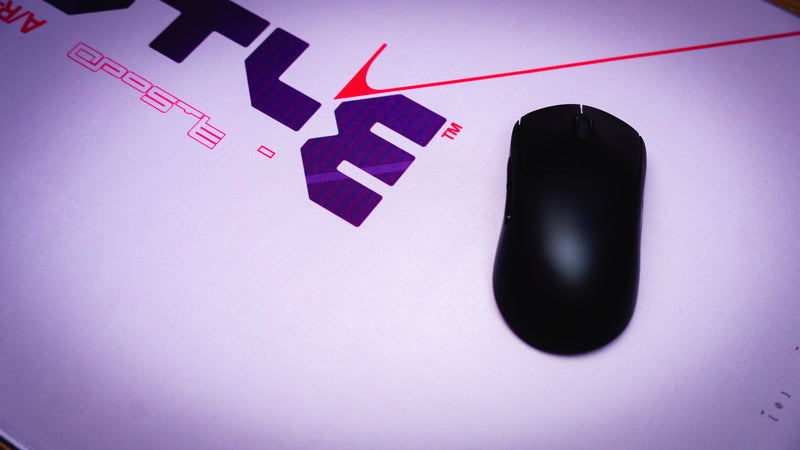 Black computer mouse on a white surface with a logo in the background