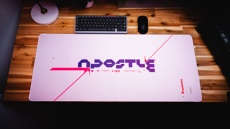 Large gaming mouse pad with 'Apostle' branding on a wooden desk.