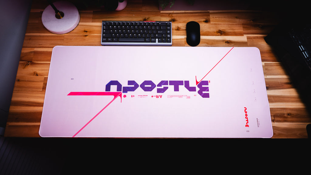 Large gaming mouse pad with 'Apostle' branding on a wooden desk.