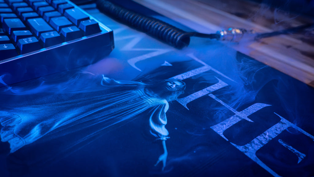 Blue-lit computer keyboard with a dark-themed graphic on a desk