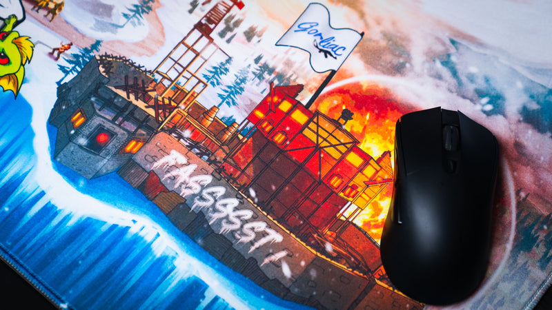 Close-up of the A Solo's Kingdom gaming deskmat by Gorliac featuring a burning Rust island base, mouse in use, and detailed snowy battlefield artwork.