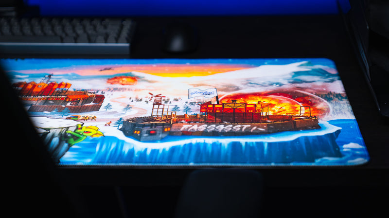 Close-up of the A Solo's Kingdom gaming deskmat by Gorliac highlighting a snowy Rust base under raid with explosions across the frozen landscape.