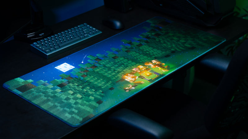 ApolloTV “Adventure Begins” XXL deskmat displayed in a gaming setup featuring a pixel-style forest campsite scene under a starry night sky.