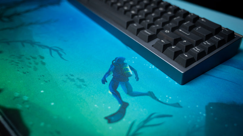 Diver artwork and fabric texture on Alidove's Lurking Leviathan deskmat beneath a black mechanical keyboard.