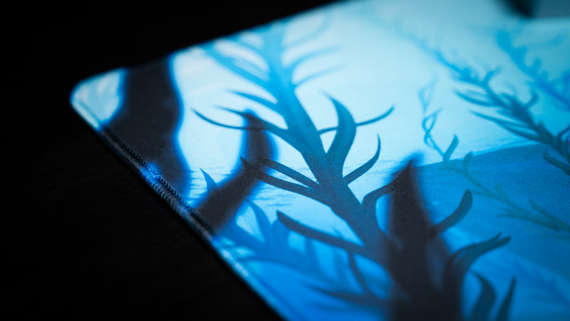 Blue kelp artwork and stitched edge detail on Alidove's Lurking Leviathan gaming deskmat.