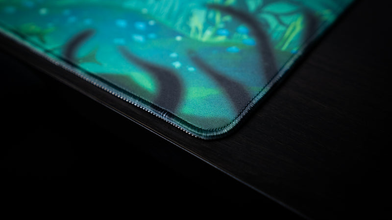 Close-up of the rounded stitched corner and teal printed fabric on Alidove's Lurking Leviathan deskmat.