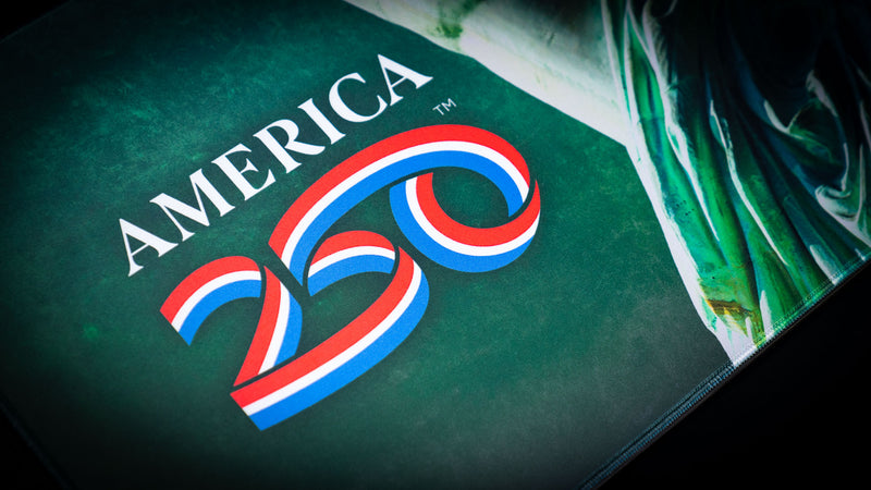 Close-up detail of the America 250 logo printed on a premium patriotic deskmat, showcasing vibrant red, white, and blue graphics on a textured green background with high-definition print quality.