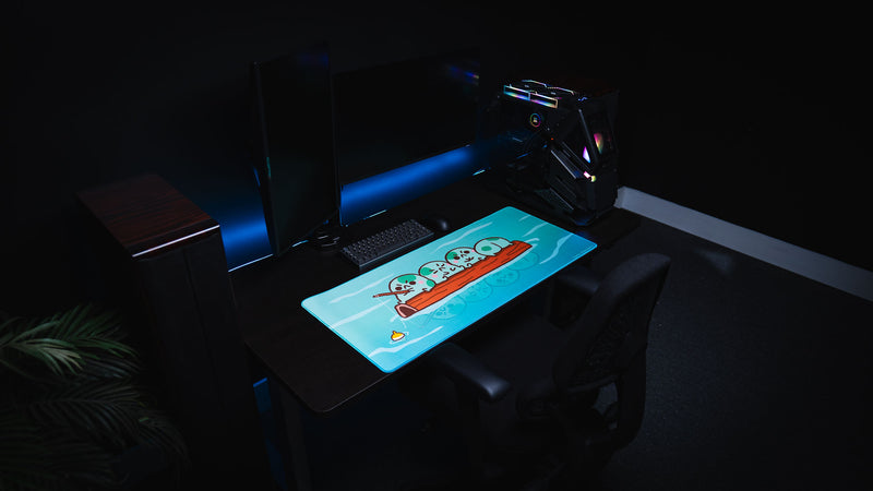Angled view of a dark gaming desk with the bright blue Angyfrog Frogs on a Log desk mat