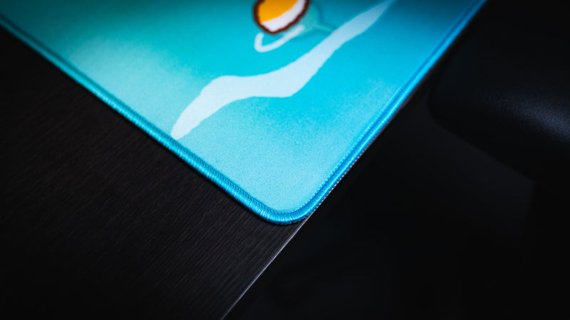 Close-up of the rounded stitched corner and turquoise surface of the Frogs on a Log desk mat