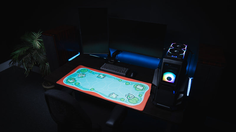 Dark gaming setup with desktop PC and the bright blue Angyfrog The Pond desk mat