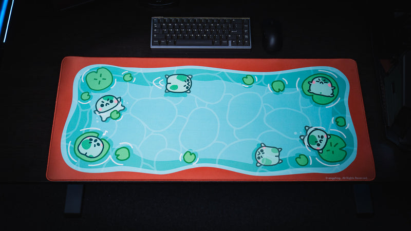 Top-down view of the full Angyfrog The Pond desk mat with frogs, lily pads, and rippling blue water