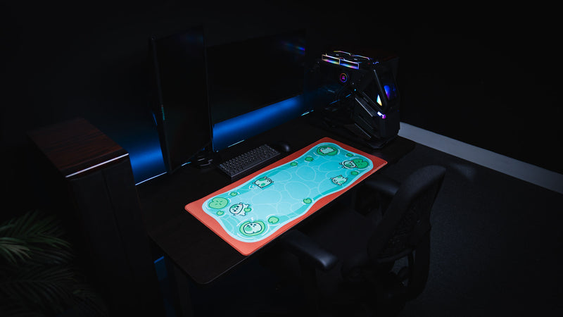 Wide RGB gaming setup with the Angyfrog The Pond desk mat glowing against a dark desktop