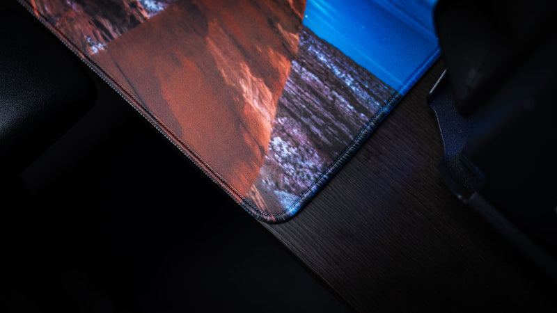 Close-up of the Arches National Park America 250 deskmat corner showing red rock artwork, blue sky detail, and premium stitched edging.
