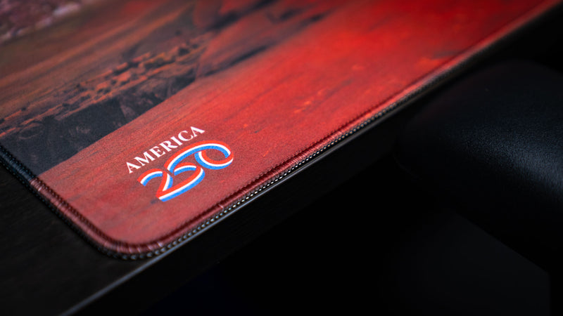 Close-up of the Arches National Park deskmat showcasing premium stitched edges, the America 250 emblem, and a high-definition landscape print.