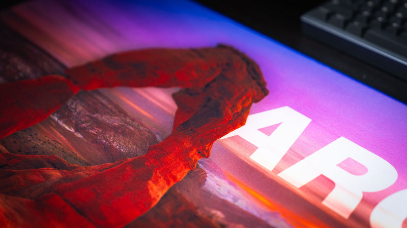 Close-up of the Arches National Park premium deskmat featuring Delicate Arch at sunset with vivid colors, high-definition print, and a smooth stitched-edge surface.