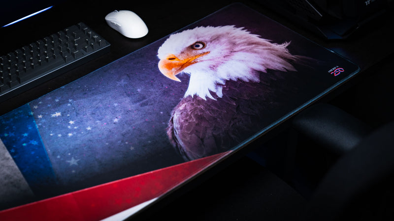 Angled close-up of the Bald Eagle America 250 deskmat featuring a bold eagle portrait, patriotic red and blue accents, star details, and stitched edges.