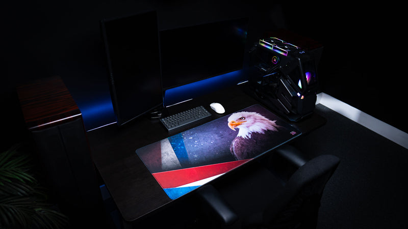 Overhead view of the Bald Eagle America 250 deskmat in a dark gaming workstation, featuring patriotic eagle artwork, star details, and red, white, and blue accents.