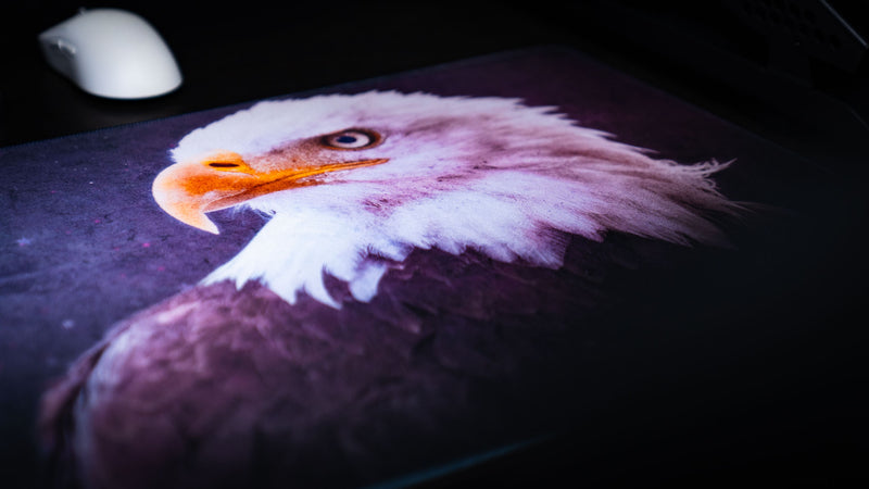Close-up of the Bald Eagle America 250 deskmat featuring a detailed eagle portrait with bold patriotic styling and a dark premium desk setup.