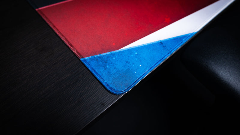 Close-up of the Bald Eagle America 250 deskmat corner showing red, white, and blue patriotic graphics with stitched edge detailing.