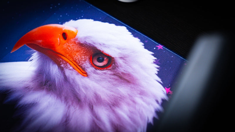 Close-up of the Bald Eagle Blue America 250 deskmat showing the eagle’s orange beak, white feathers, and blue star background.