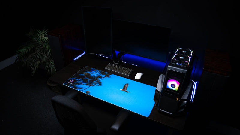 Lifestyle photo of the Bald Eagle in Flight deskmat displayed on a modern gaming setup, featuring a soaring bald eagle against a vivid blue sky as part of the America 250 collection.