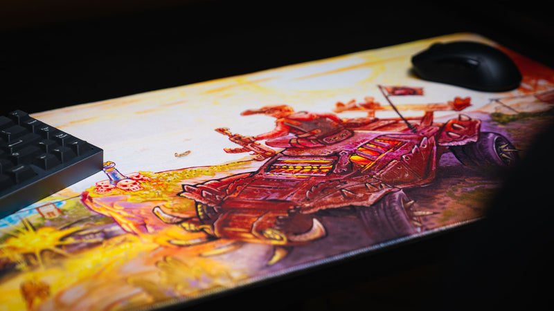 Angled view of the Rust After Glory desk mat beneath a keyboard and mouse, highlighting the armored vehicle art