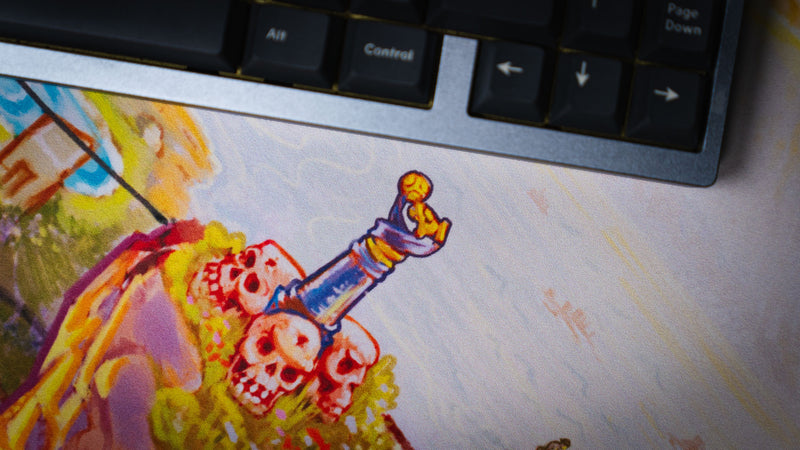 Detailed print close-up of skulls and a sword on the Rust After Glory desk mat beside a keyboard