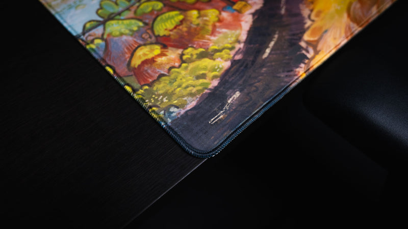 Close-up of the reinforced stitched corner and colorful road artwork on the Rust After Glory desk mat