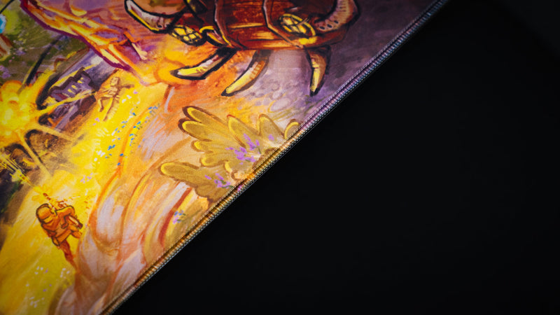Close-up of the Rust After Glory desk mat edge with a survivor, explosion, and armored vehicle details