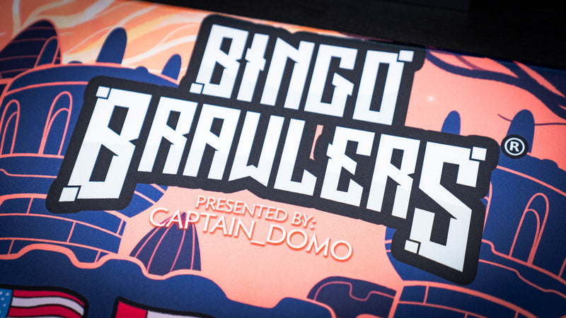 Close-up of the Bingo Brawlers Season 6 Commemorative Deskmat logo featuring Captain Domo branding and fantasy castle artwork.