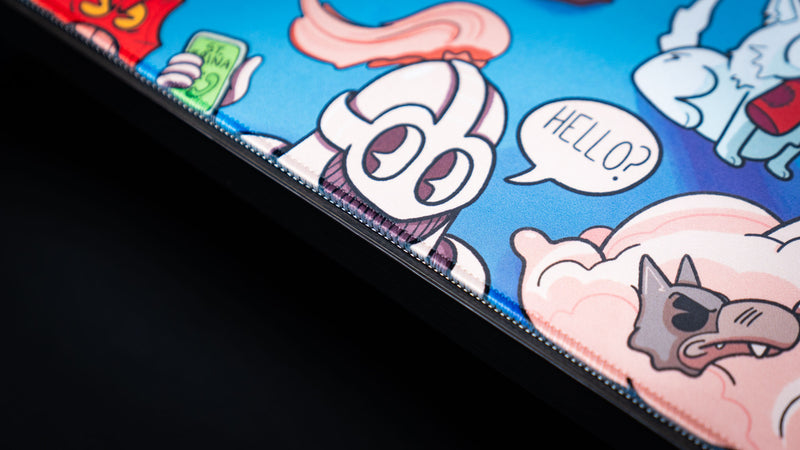 Close-up of the Bingus Bongus deskmat showcasing premium stitched edges, vibrant print quality, and character artwork with speech bubble details.