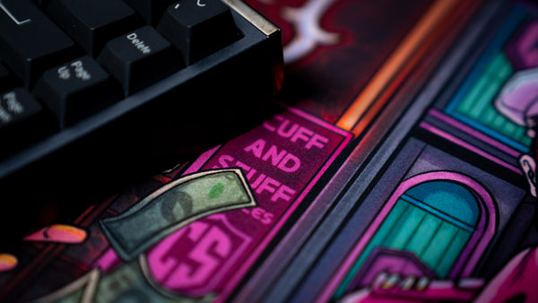 Close-up of the BobbyRayGray BRG Loading deskmat highlighting vibrant comic-inspired artwork with neon storefront details, floating cash, and premium print quality.