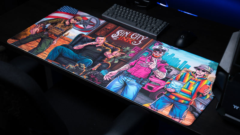 BobbyRayGray BRG Loading creator collaboration deskmat featuring vibrant comic-style Sin City Ink artwork displayed on a premium XXL gaming desk setup.