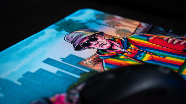 Close-up of the BobbyRayGray BRG Loading deskmat featuring a colorful rainbow hoodie character with a city skyline backdrop on a premium gaming deskmat.