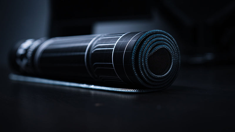 Rolled BRAINBOX MK1 deskmat showcasing flexible construction, stitched edges, and premium gaming deskmat craftsmanship.