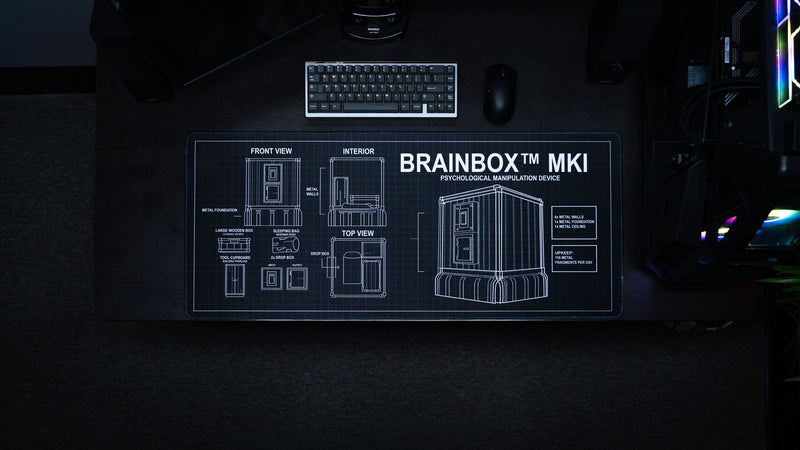 Top-down view of the BRAINBOX MK1 deskmat featuring detailed Rust base blueprints, technical schematics, and engineering-inspired artwork.