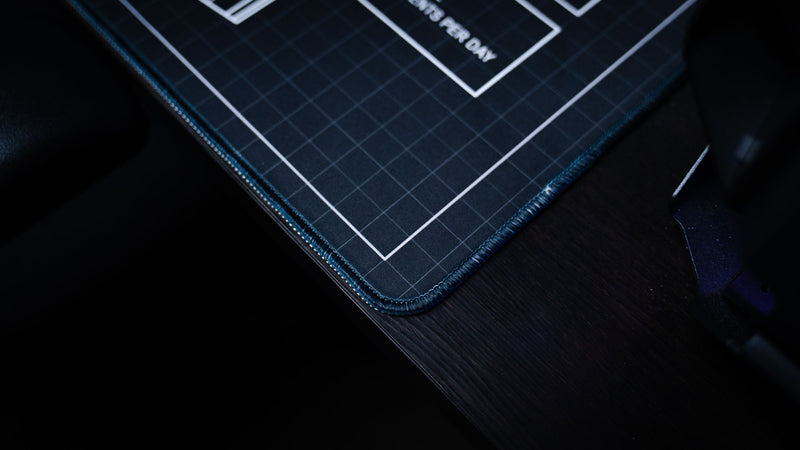 Close-up of the BRAINBOX MK1 deskmat showcasing premium stitched edges, blueprint grid artwork, and high-quality construction.