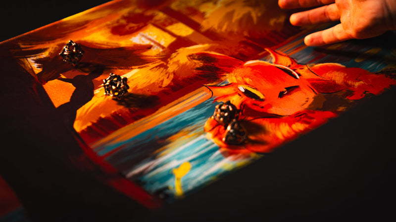 Metal gaming dice rolling across the Bubbles Playmat by Exodo Studios during tabletop play under warm lighting