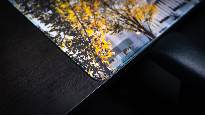 Close-up of the Capitol Building deskmat corner highlighting premium stitched edges, vibrant autumn foliage, and the high-definition print quality of the extended mouse pad.