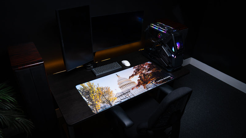 Premium Capitol Building deskmat displayed in a modern gaming and office setup, featuring the U.S. Capitol surrounded by colorful autumn trees with a full-desk workspace view.