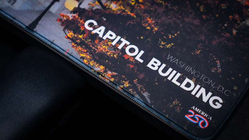 Close-up of the Capitol Building deskmat showcasing the Washington, D.C. title, America 250 logo, premium stitched edges, and vibrant autumn colors printed on a high-definition extended mouse pad.
