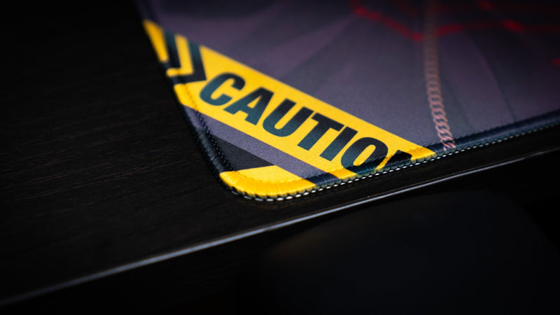 Close-up of the stitched corner and yellow caution graphic on the CelisEris Brand Risk playmat