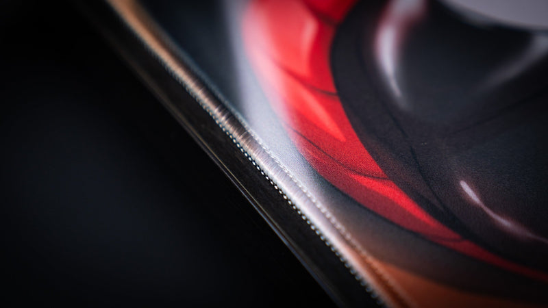 Close-up of the stitched edge and red sleeve artwork on the CelisEris Martial TCG playmat
