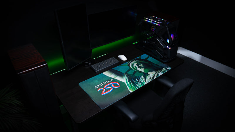 Close-up Statue of Liberty deskmat displayed on a modern gaming desk with dual monitors, showcasing the premium HD print, stitched edges, and oversized extended mouse pad design.