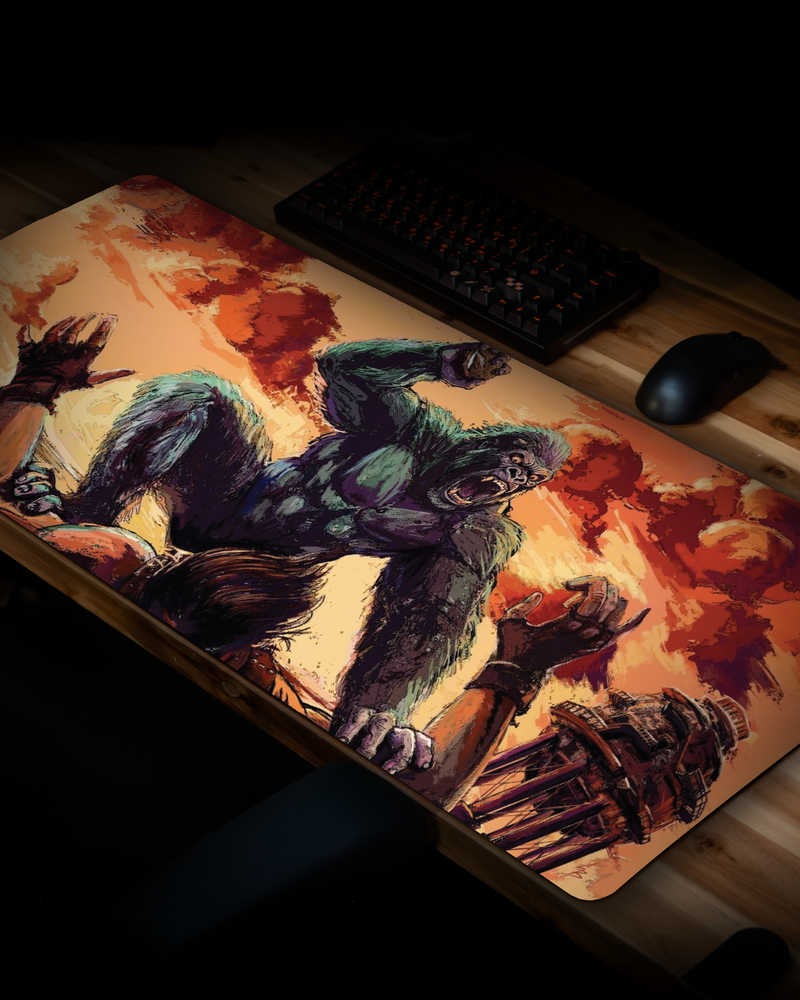 CocoKong gaming deskmat displayed on a desktop setup, featuring a giant gorilla attacking in a Rust-inspired beach scene at sunset.