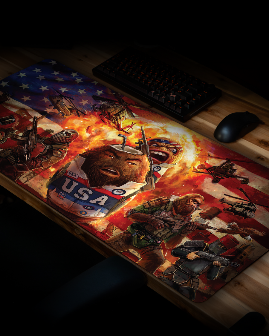 Angled view of the CoconutB USA Mousepad featuring patriotic Rust-inspired artwork with helicopters, armed survivors, explosions, and a premium gaming desk setup.