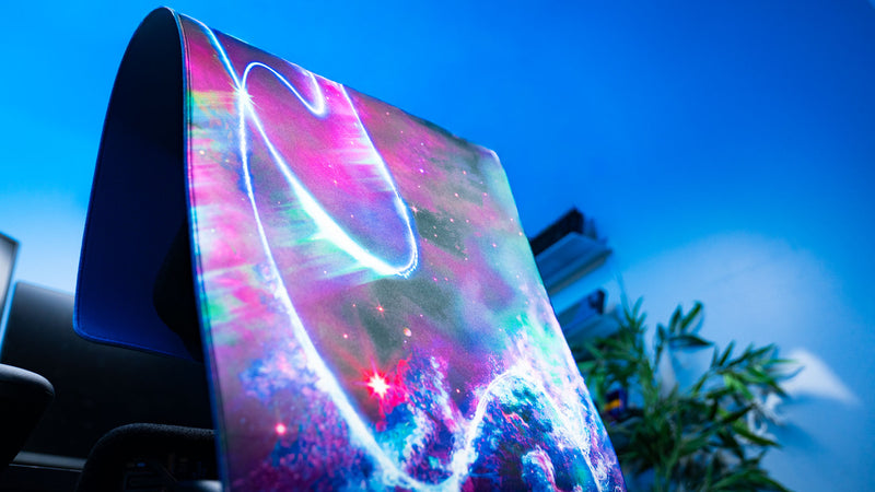 Vertical showcase of the Cosmic TV XXL deskmat featuring glowing cosmic trails, nebula artwork, and vibrant retro sci-fi colors.