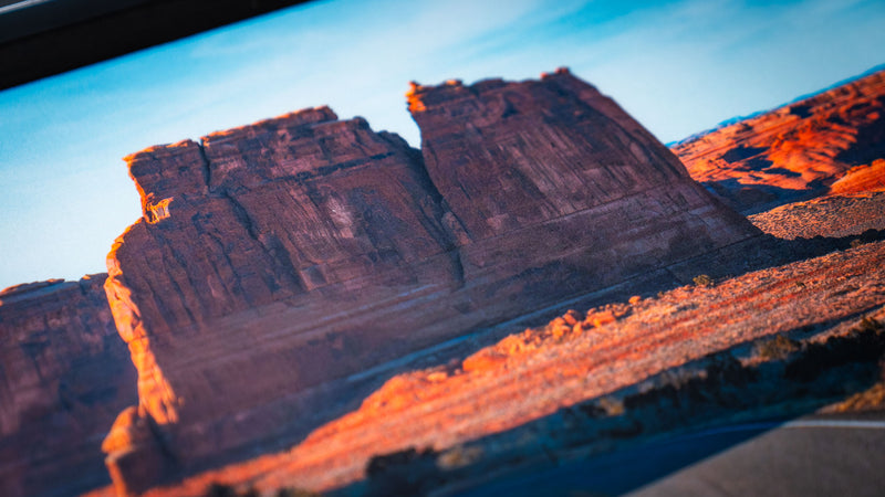 Close-up of the Courthouse Towers America 250 deskmat showing massive sandstone rock formations, warm desert lighting, and printed fabric texture.