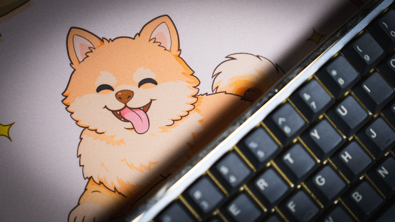 Close-up of the Cozy Desk deskmat featuring a happy cartoon Pomeranian surrounded by warm autumn colors and a soft pastel aesthetic.