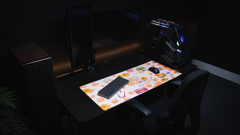 Cozy Desk deskmat displayed on a minimalist gaming desk featuring autumn leaves, sunflower accents, cute illustrations, and a soft pastel fall aesthetic